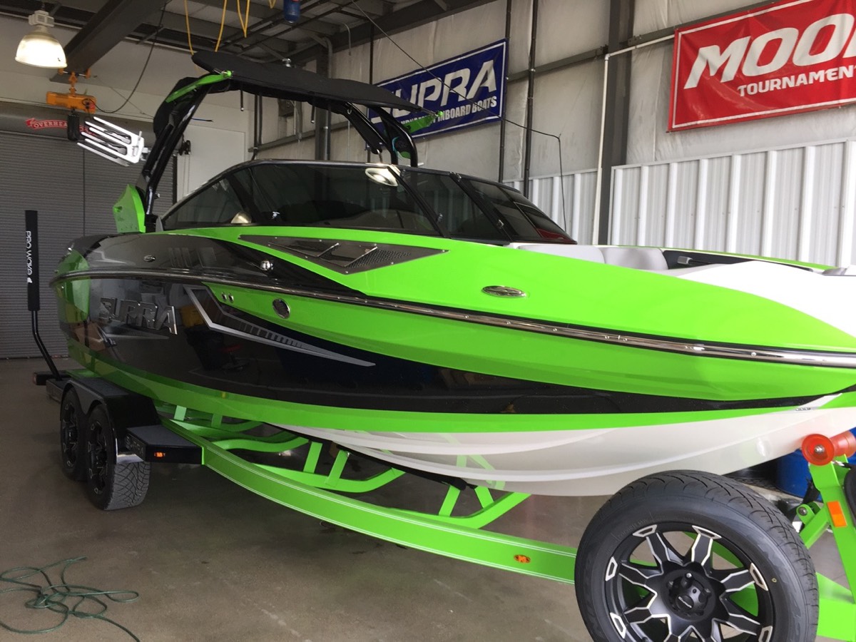 Green and black Supra wake boat with tinted windshield
